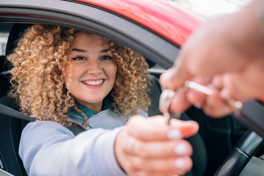 Happy woman giving car keys to personal valet